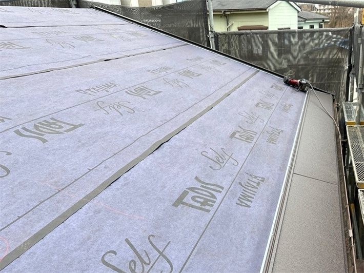 屋根カバー工事にてスーパーガルテクトを葺く様子