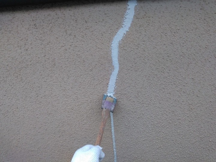 亀裂にコーキング材を充填した後にヘラで整える作業