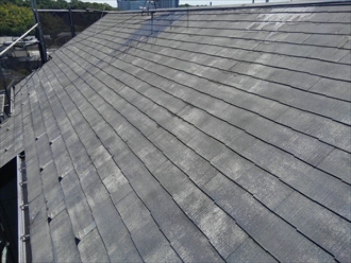 屋根に高圧洗浄する作業風景