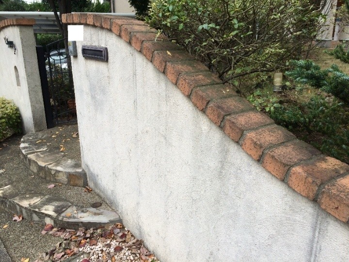 上端のレンガ目地から滴り落ちた汚れの跡が目立っている擁壁