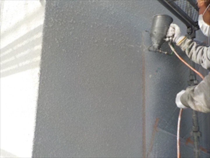 玉吹き専用の塗料を使って外壁に吹き付ける作業風景