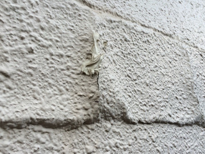 塗膜がモルタルから剥がれかけて浮いている状態