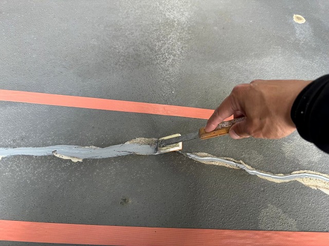 ひび割れに変成シリコン系弾性接着剤を充填した後にヘラで押さえている様子