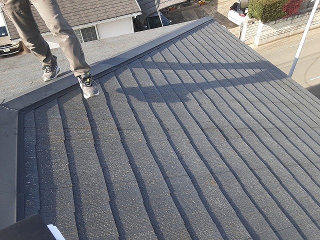 屋根の上でスレート屋根の劣化症状を確認する調査員