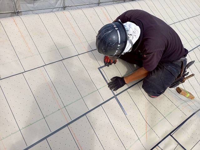 屋根葺き替え工事の瓦残を取り付けるための墨出しを行う屋根職人