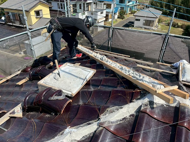 屋根棟瓦取り直し工事で型枠の中に漆喰材を詰め込んでいる様子