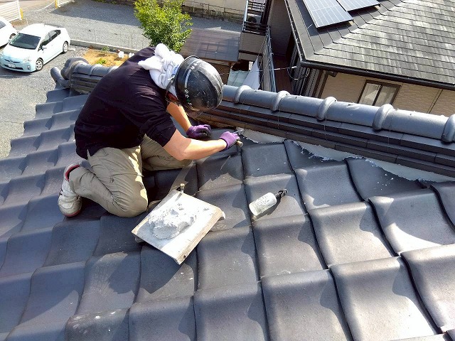 職人が隅棟に漆喰をコテで詰め込んでいる作業の様子