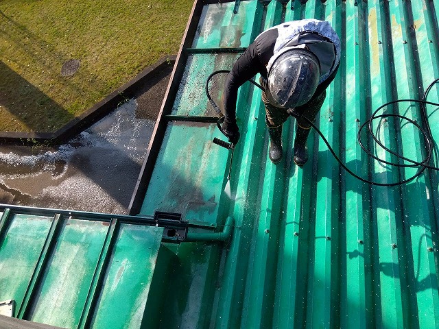 金属屋根の端部を高圧洗浄機で洗浄している様子