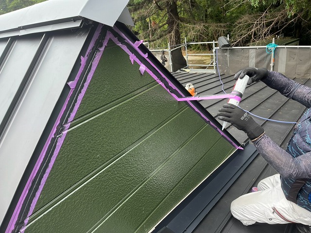 外壁面の周囲をマスキングテープで養生し、板金との隙間へコーキングを充填する様子