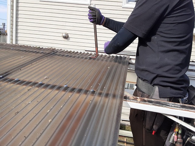 波板張り替え工事で既存波板屋根の傘釘をバールで引き抜き