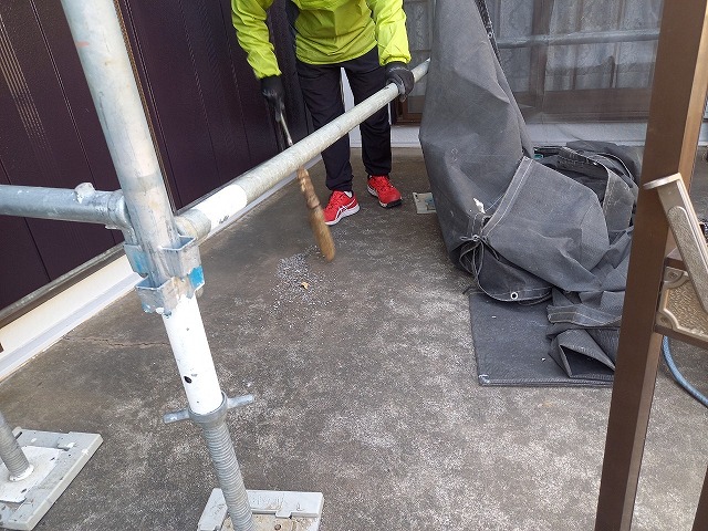 外壁塗装リフォームの施工後に掃き掃除を行う職人