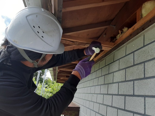 軒天張り替え補修を行うためノミと金槌で既存の軒天を撤去している様子