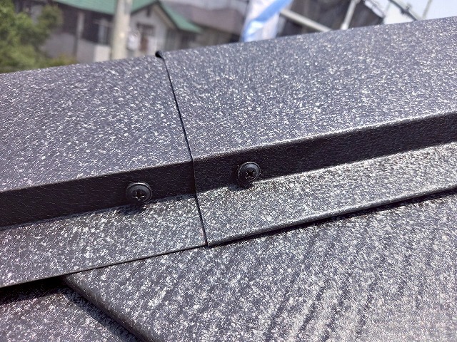 屋根カバー工事で棟包み部材をビス固定している状況