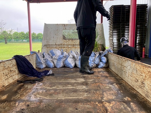 工場建物の雨樋清掃メンテナンスで発生したゴミを車両に積み込んでいる様子