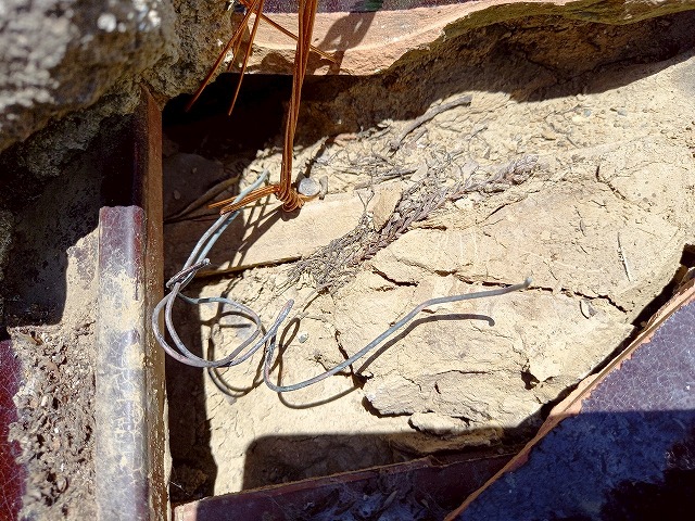 崩れ落ちていた店舗建物の棟を補修するため番線を屋根下地に留め付けている様子