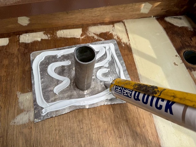 ベランダ防水工事で改修用ドレンの裏側にコーキング材を塗布している様子