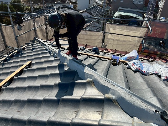 屋根葺き直し工事で隅棟部に漆喰材「モルロック」を塗り付けて成形している屋根職人