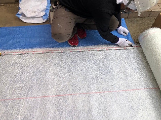 FRP防水メンテナンスでガラス繊維マットをカットしている様子