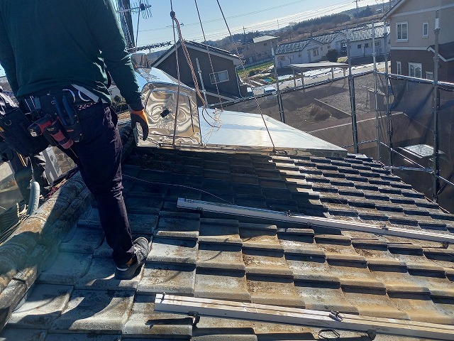 葺き替え工事で取り外した太陽熱温水器をユニック車で搬出している状況