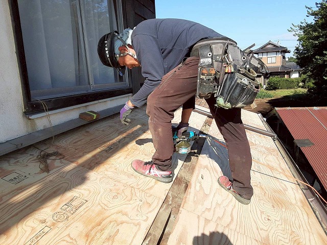 屋根葺き替え工事の野地板増し張り工程で構造用合板を釘打ちしている状況
