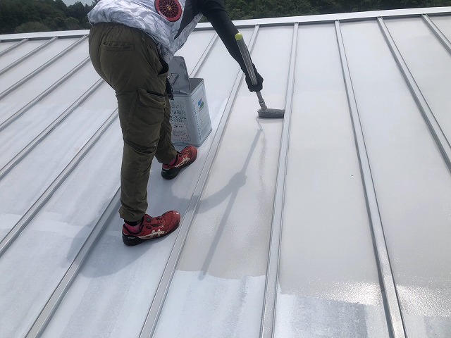 エスケープレミアムルーフSiを用いてローラーで金属屋根に中塗りを行う様子