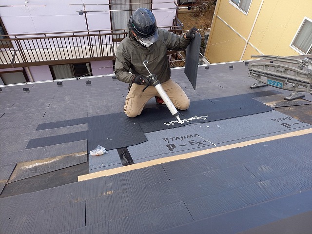 雨漏り修理のためのトップライト撤去工事でスレート屋根に接着剤を塗布