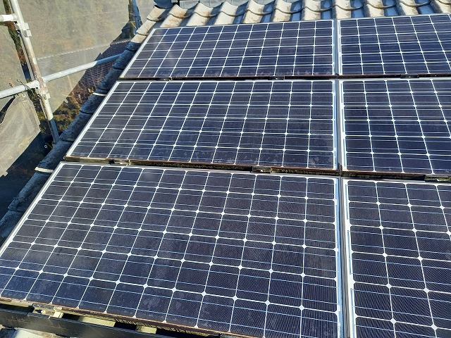 葺き替え工事を行う住宅の屋根に太陽光パネルや太陽熱温水器が設置されている状況