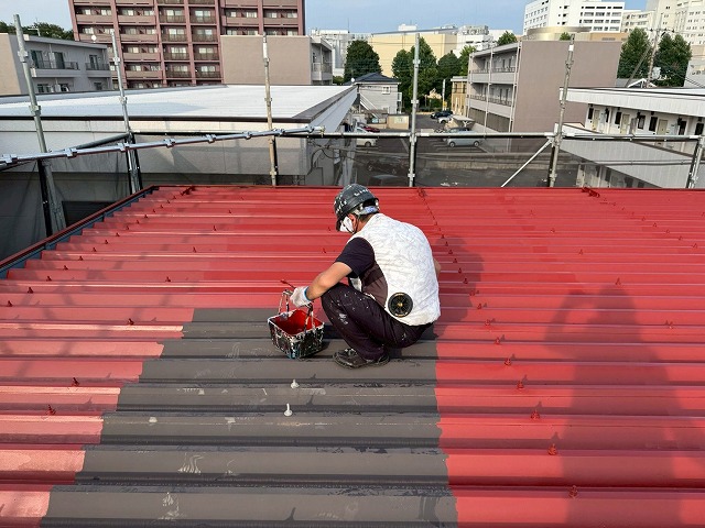 アパート折板屋根塗装工事で「マイルドボーセイ」による下塗りを行う塗装職人