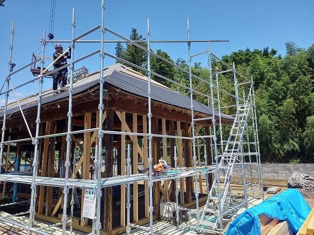 平屋住宅の屋根上で葺き替え工事を行う屋根職人