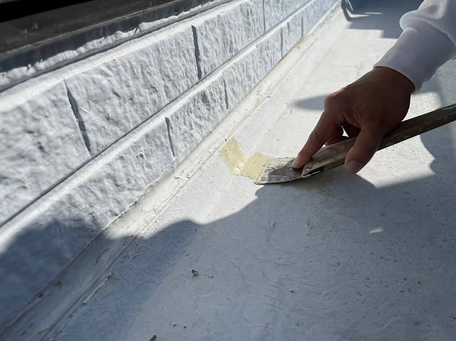 ベランダ防水メンテナンス下地処理工程のヘラを用いたパテ補修