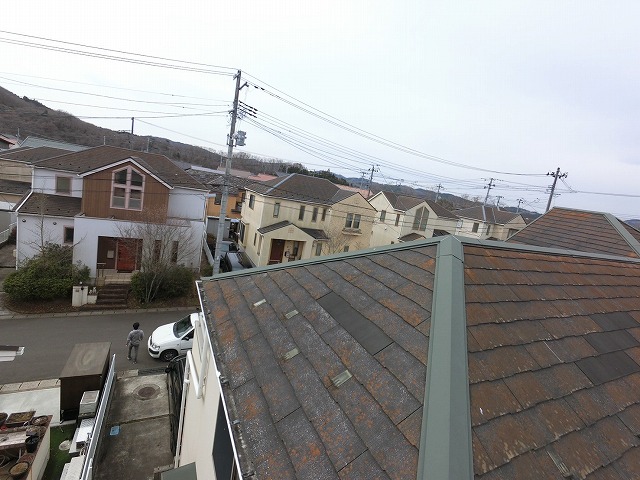 スレート屋根の表面にオレンジの苔が目立つ