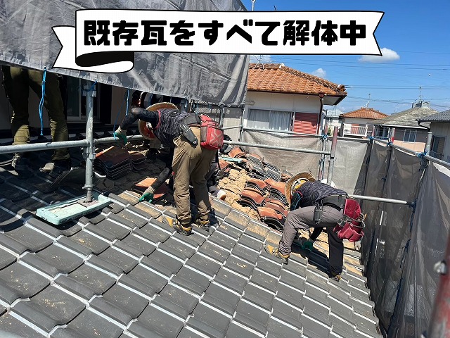 職人が屋根の上で既存瓦を一枚ずつ剥がし、積み重ねている様子