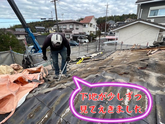 軒先で固着した屋根材を工具でこじって外す職人の手元アップ