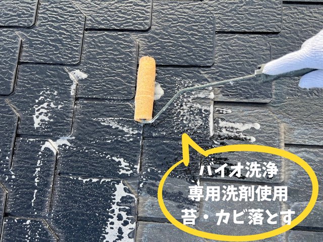 黄色ローラーで黒いスレートに発泡した洗剤を塗り広げている手元のアップ。