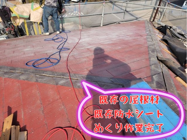 赤い既存スレート面に残った桟木跡を点検・清掃している状況