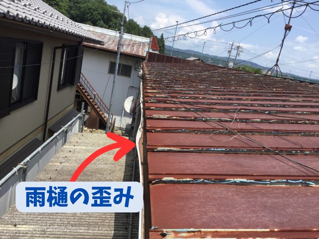 歪んで傾いた店舗屋根の雨樋