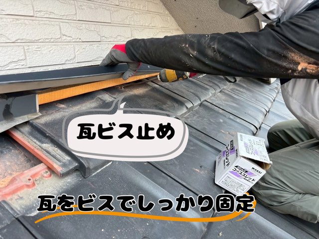 作業員がインパクトを使って瓦と下地をビスで固定している様子。黒瓦と下地木材が見えており、強風対策のための工程