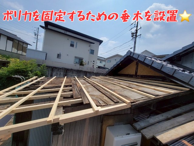 「木材の下地が一部取り除かれ、新しい垂木を並べている途中の作業風景。