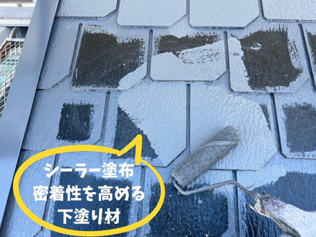 ローラーでグレーの下塗りを行い、タイル状のスレートに艶が出ている写真。