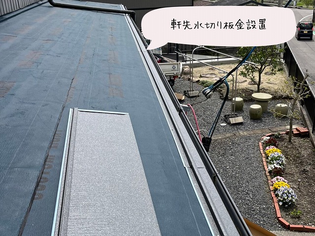 軒先に銀色の板金を取り付けている様子。雨水の流れを整えるための作業。