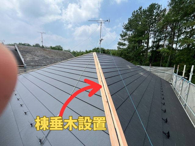 新しい棟板金を支えるために、屋根のてっぺんに棟垂木（木材）を取り付けている様子