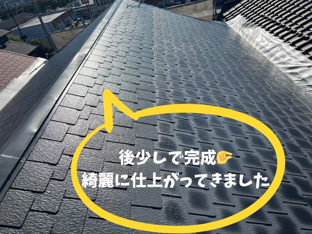 陽光に照らされ、艶のあるスレート屋根が奥まで続く完成直前の全景。