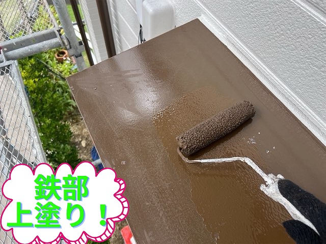 鉄部に上塗りをしている様子。茶色の塗料をローラーで塗布。