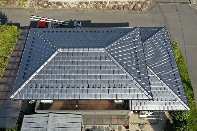 屋根葺き替え工事完了後の可児市桜ケ丘のお住まいを上空から撮影した写真。瓦の並びが整い、棟部分もきれいに仕上がった屋根全体の様子。