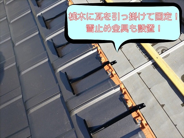 防水シートと桟木を施工した屋根に、雪止め金具を取り付けた平板瓦の施工途中の様子