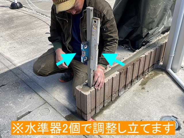 水平器二個を用いてフェンス支柱を立てる