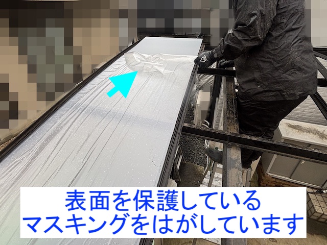 車庫の上にパネルを載せ、マスキングを剥がしている風景