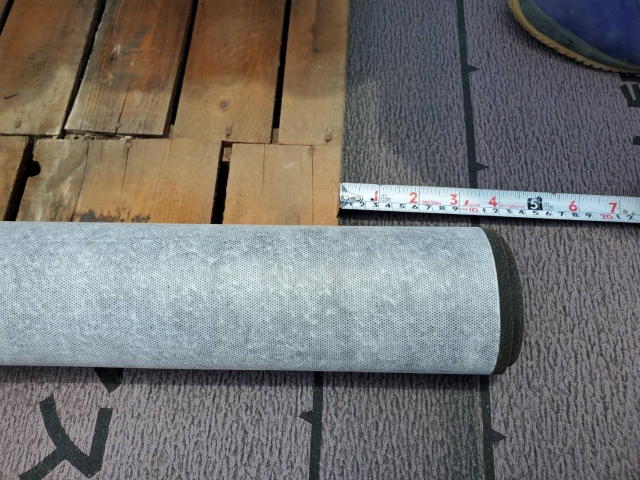 新しいルーフィングを軒先側から上に向かって丁寧に施工しています