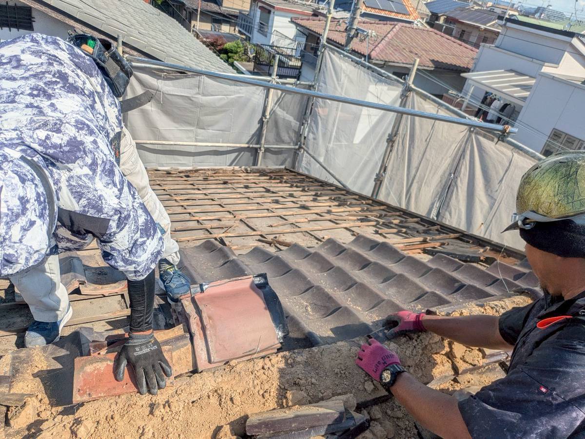 職人が瓦を丁寧に剥がしているところ