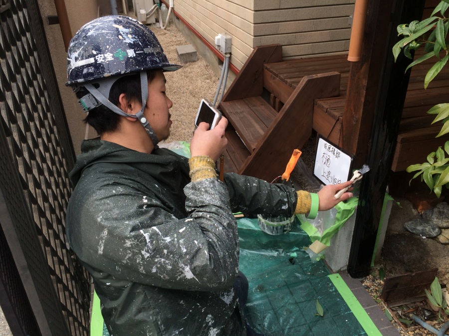 雨樋の上塗りの様子を写真を撮っている職人さんの写真